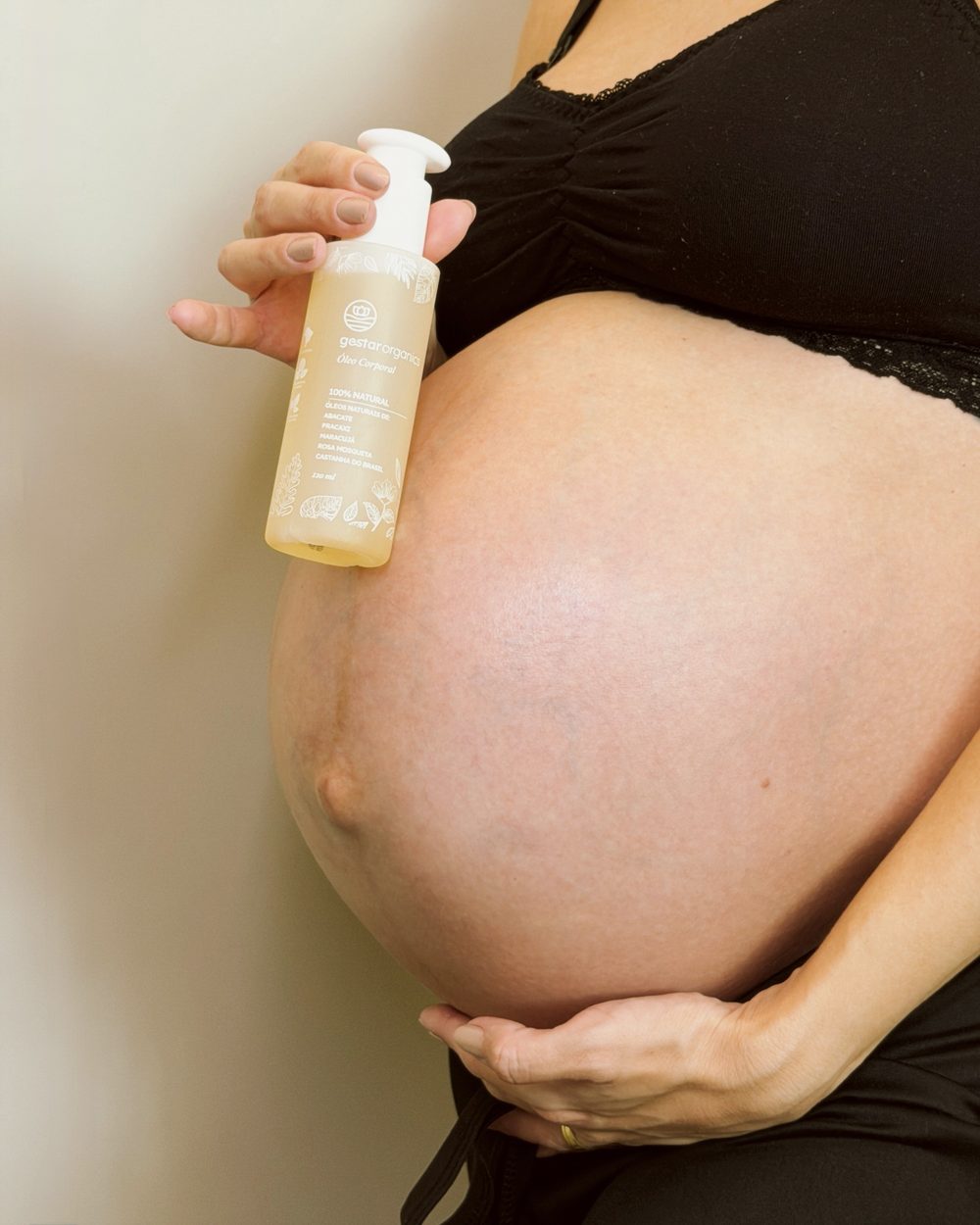Gestante segurando o Óleo Corporal Anti-Estrias junto à barriga